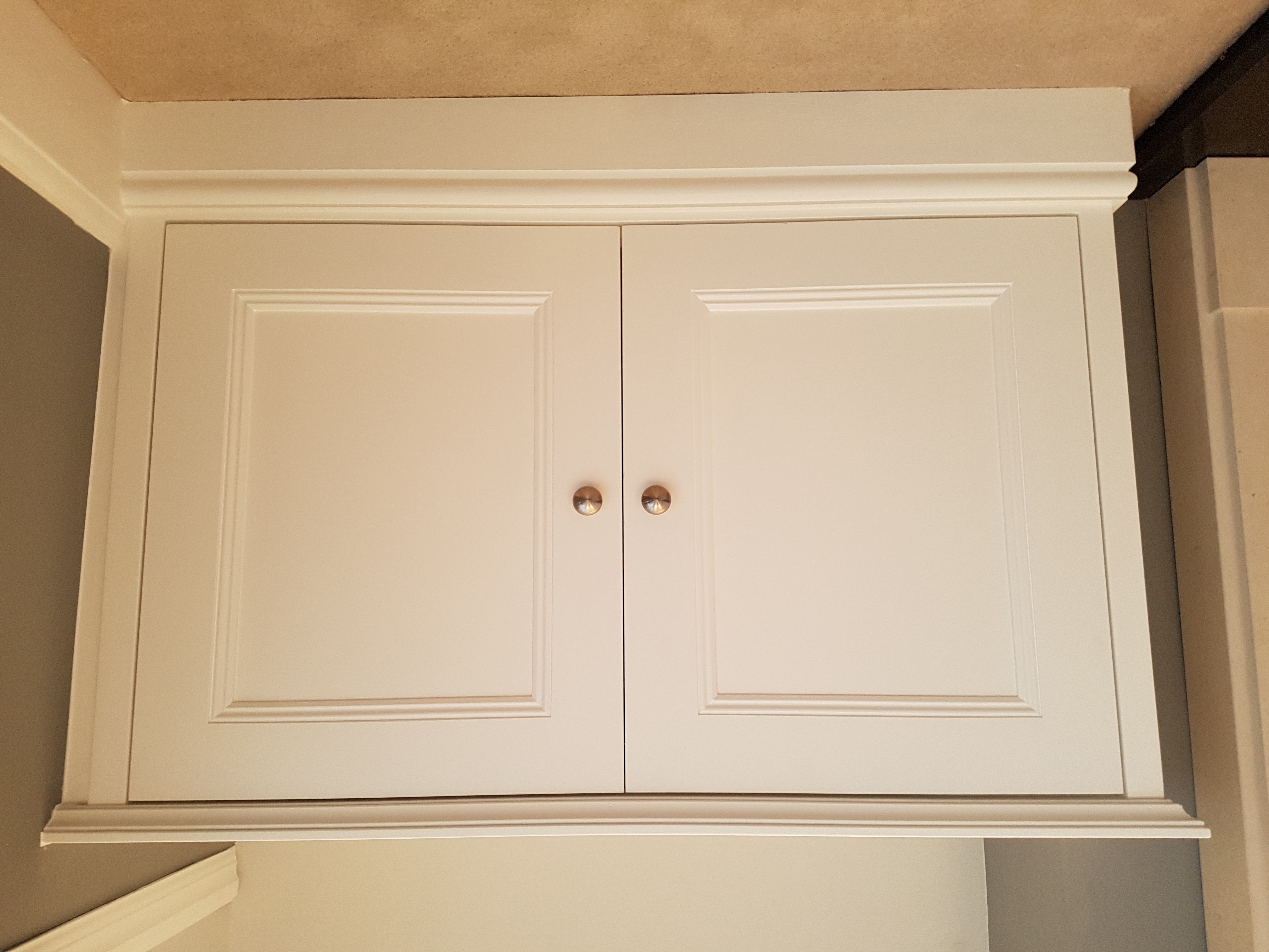 Traditional built-in storage cabinet in Timeless cream paint with brass knobs, ideal for a living room.