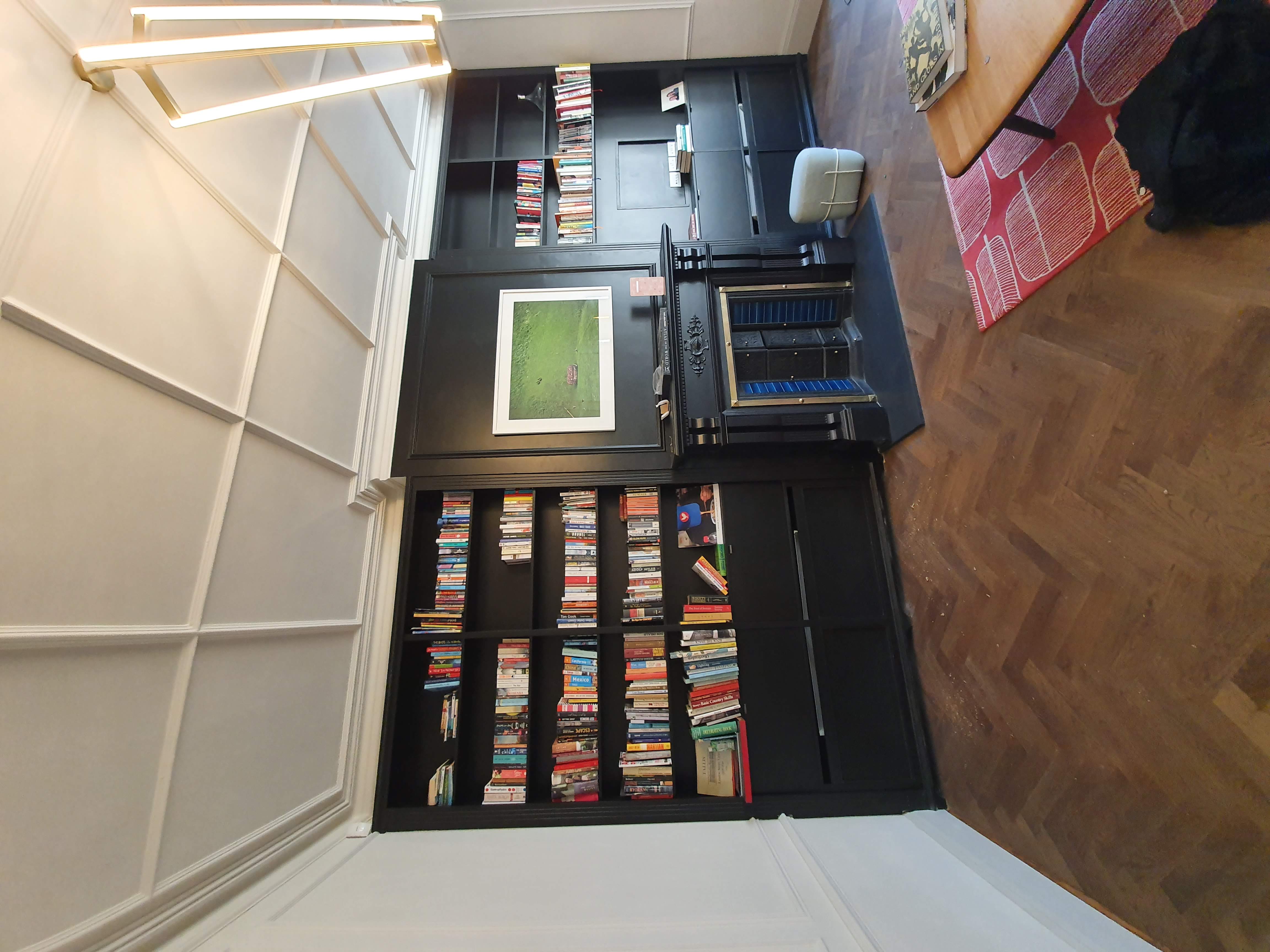 Fitted Traditional dark grey bookcase in a living room, featuring open shelving for books and integrated storage cabinets with grille panels.