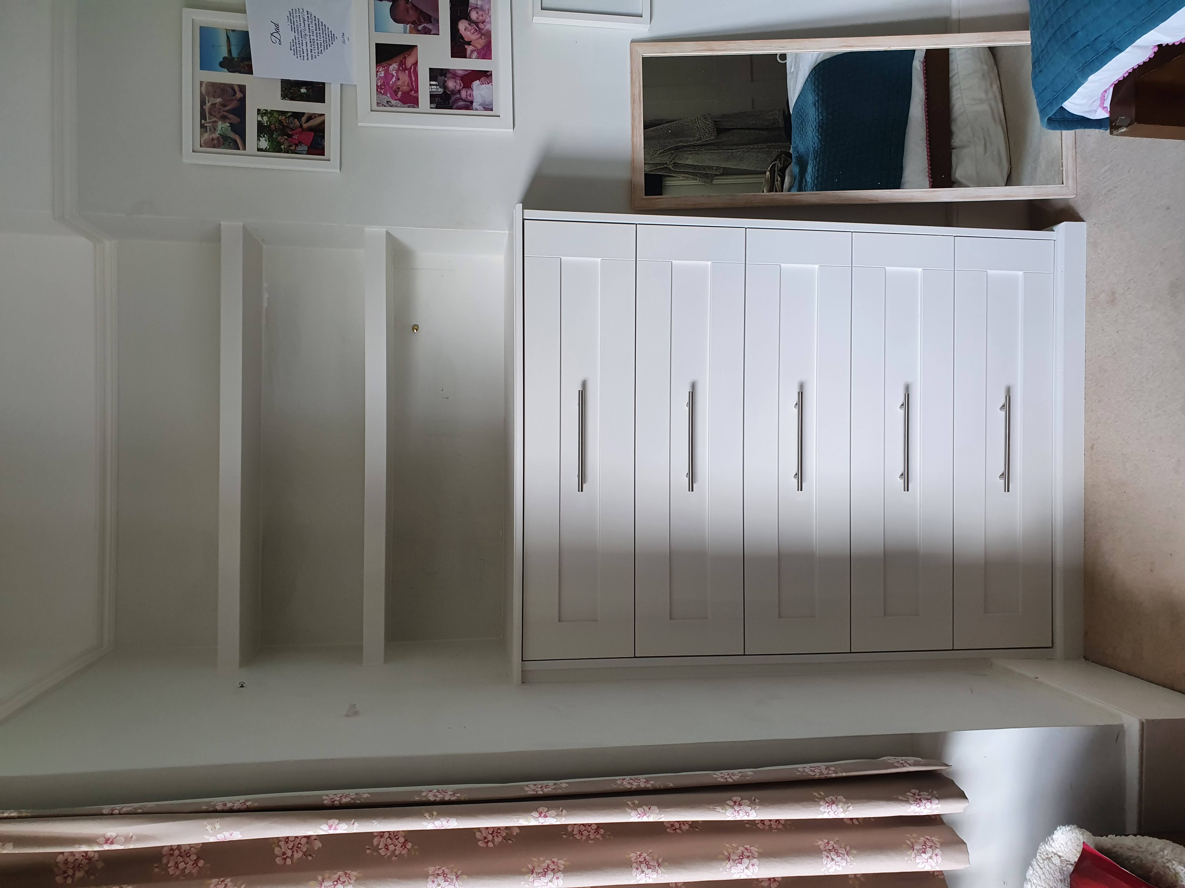 Traditional light blue fitted wardrobe with mirrored shaker doors and brass knobs in a bedroom