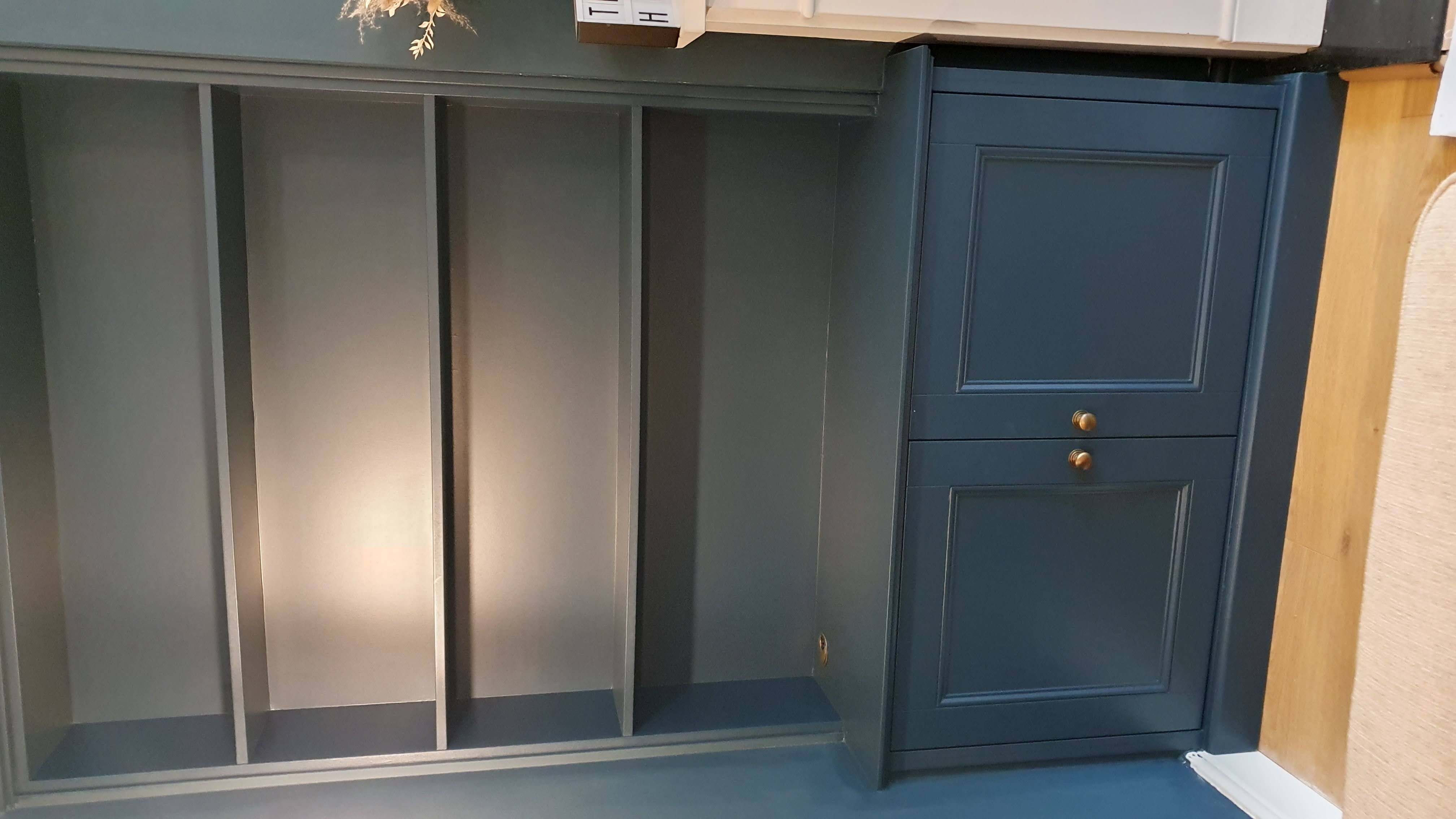 Traditional built-in storage cabinets painted in Farrow and Ball Hague Blue with brass knobs, ideal for a living room.
