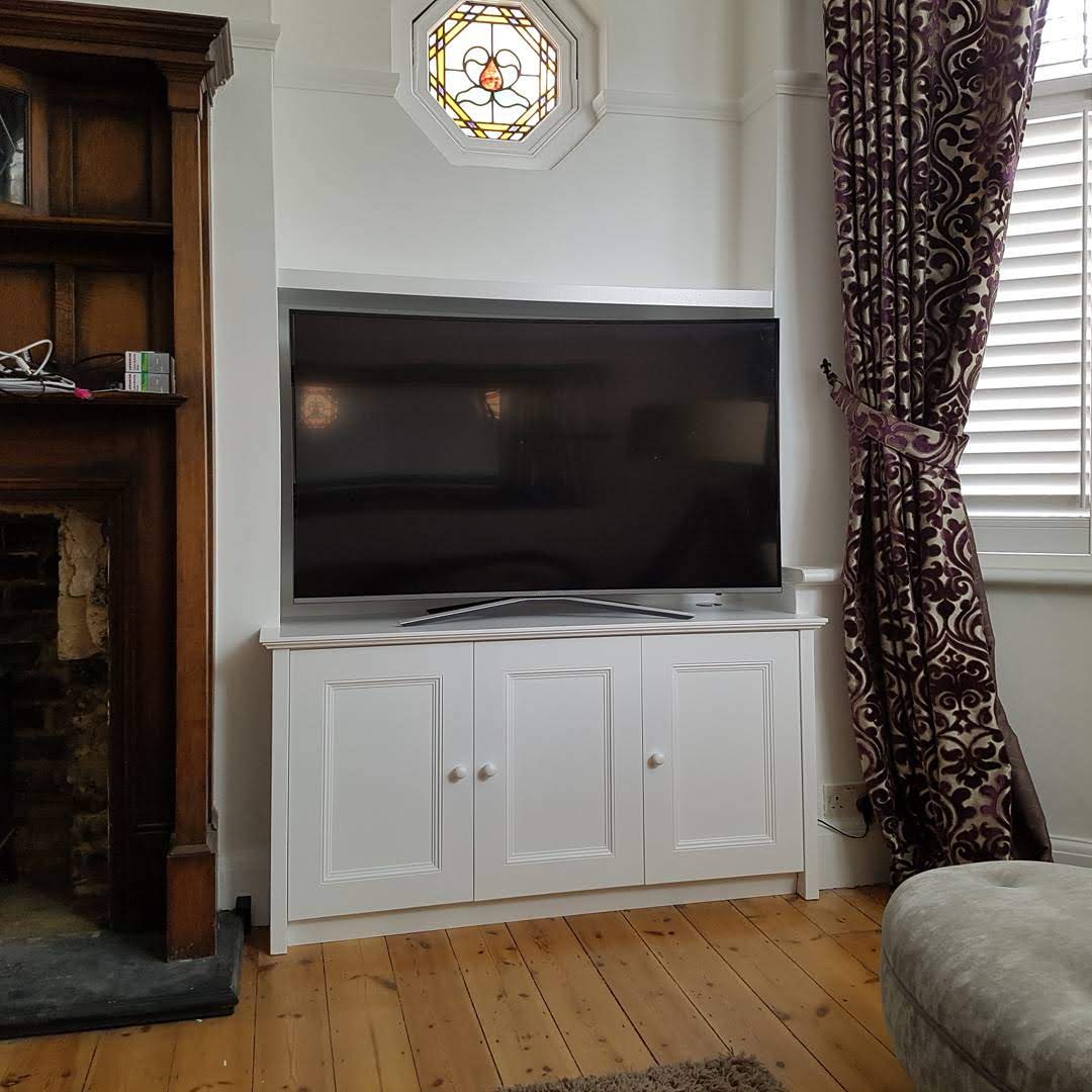 Contemporary white alcove unit with floating shelves and push-to-open cabinets in a living room.