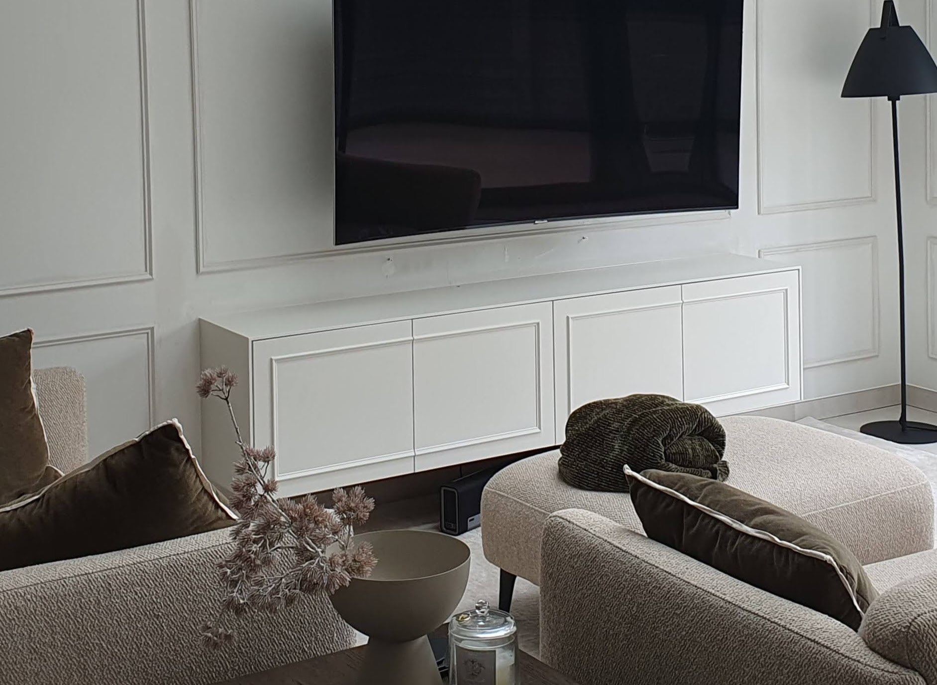 Elegant white built-in storage unit in a traditional style living room, beneath a wall-mounted TV.