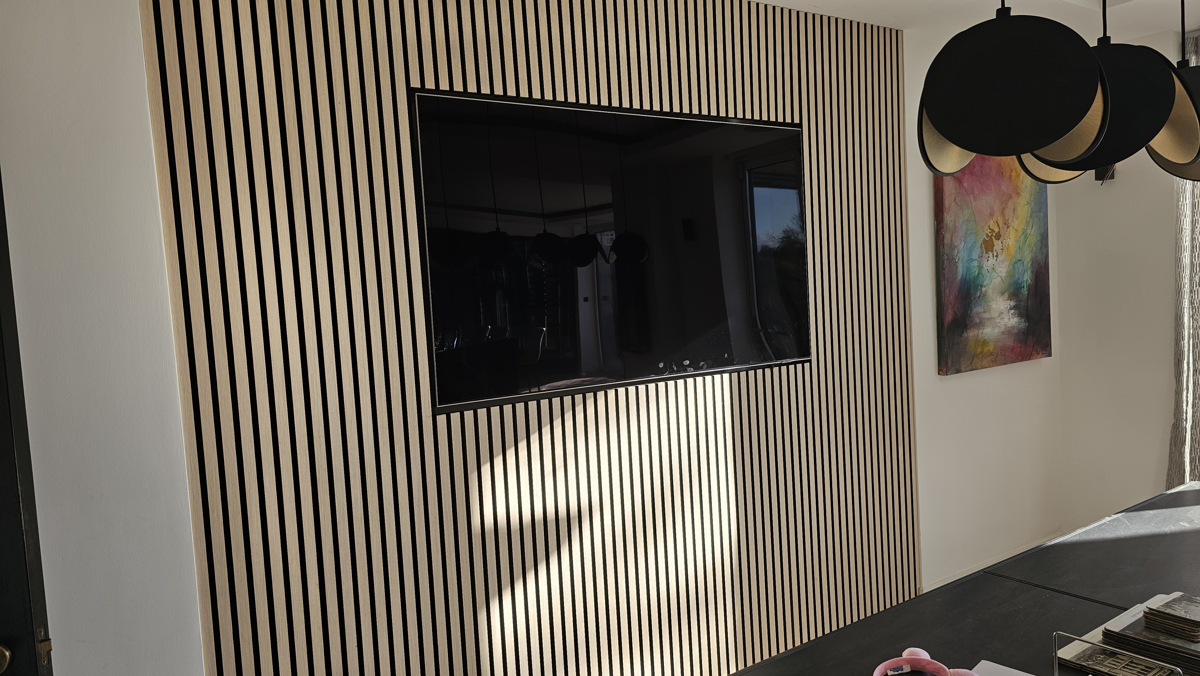 Modern natural oak slatted wall paneling in a living room, featuring a seamlessly integrated television.