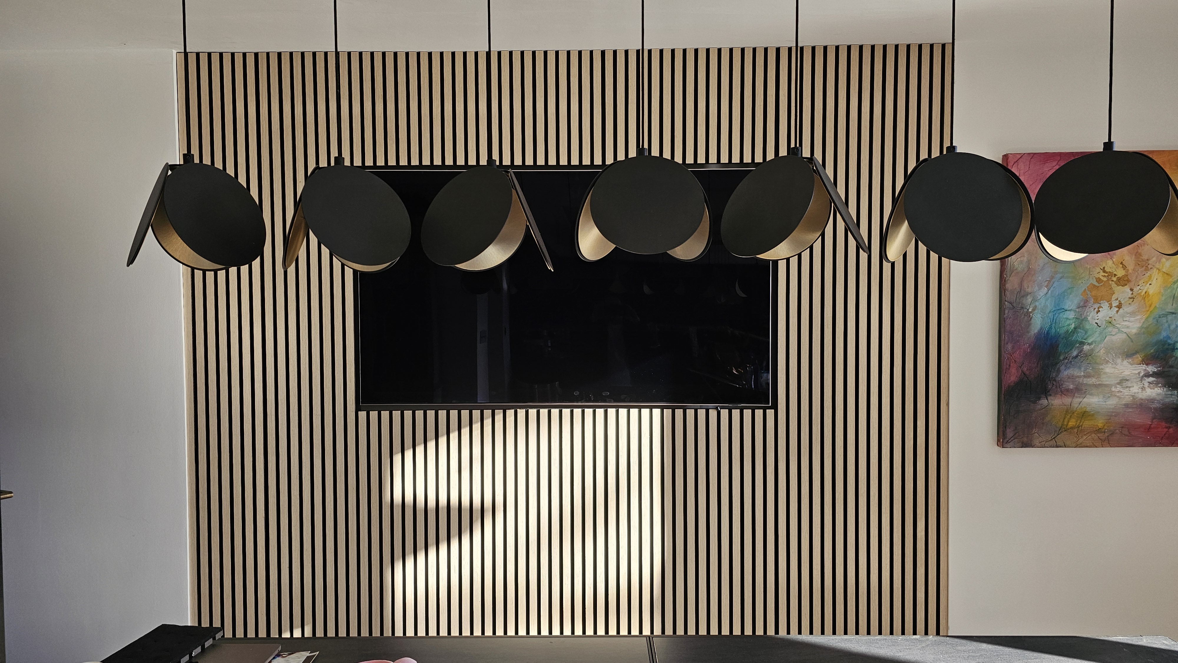 Modern minimalist fitted TV unit in natural oak slatted wood paneling for a living room.