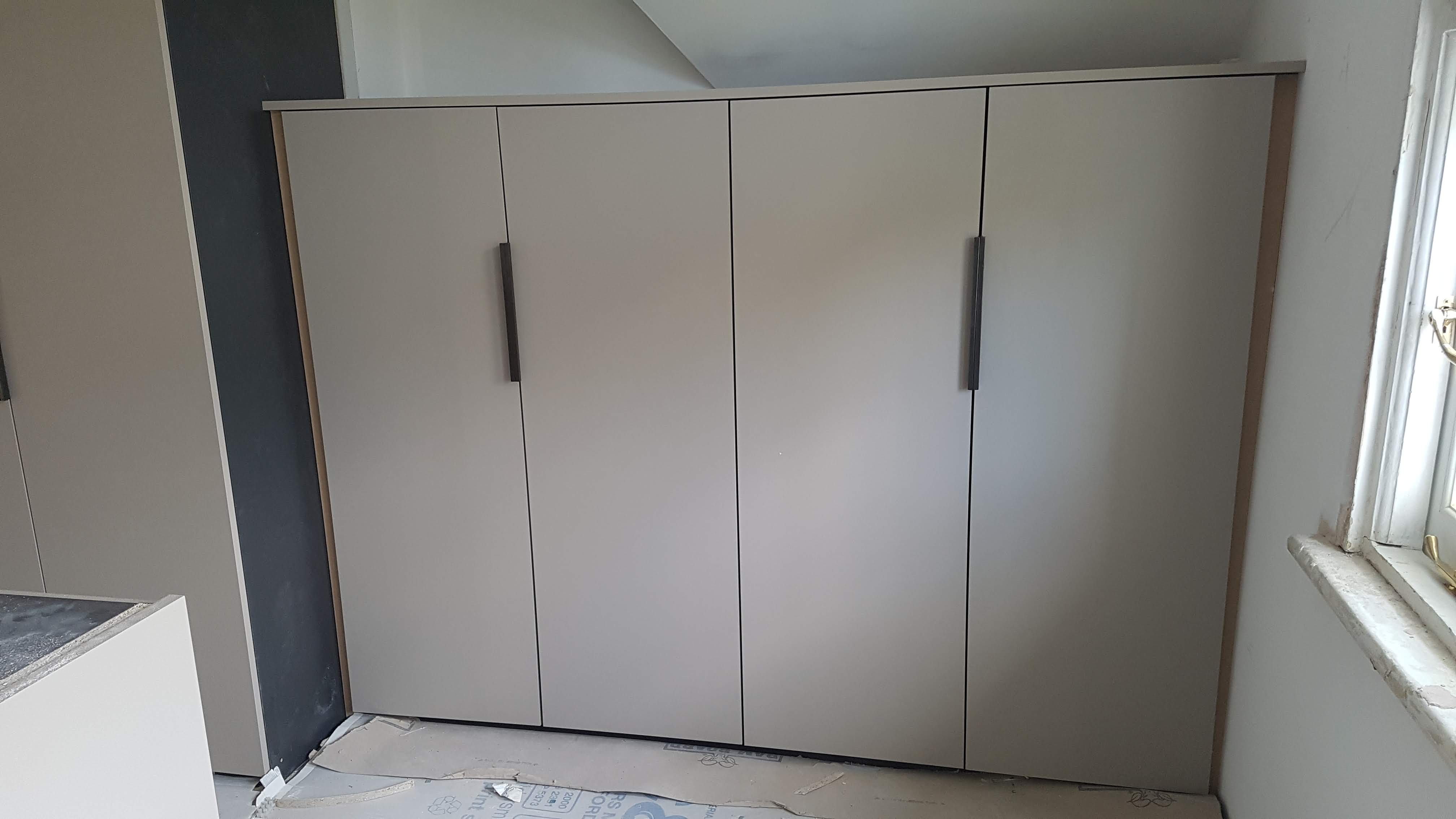 Modern fitted wardrobe in Skimming Stone a Farrow and Ball neutral, with matte black bar handles, perfect for a contemporary bedroom.