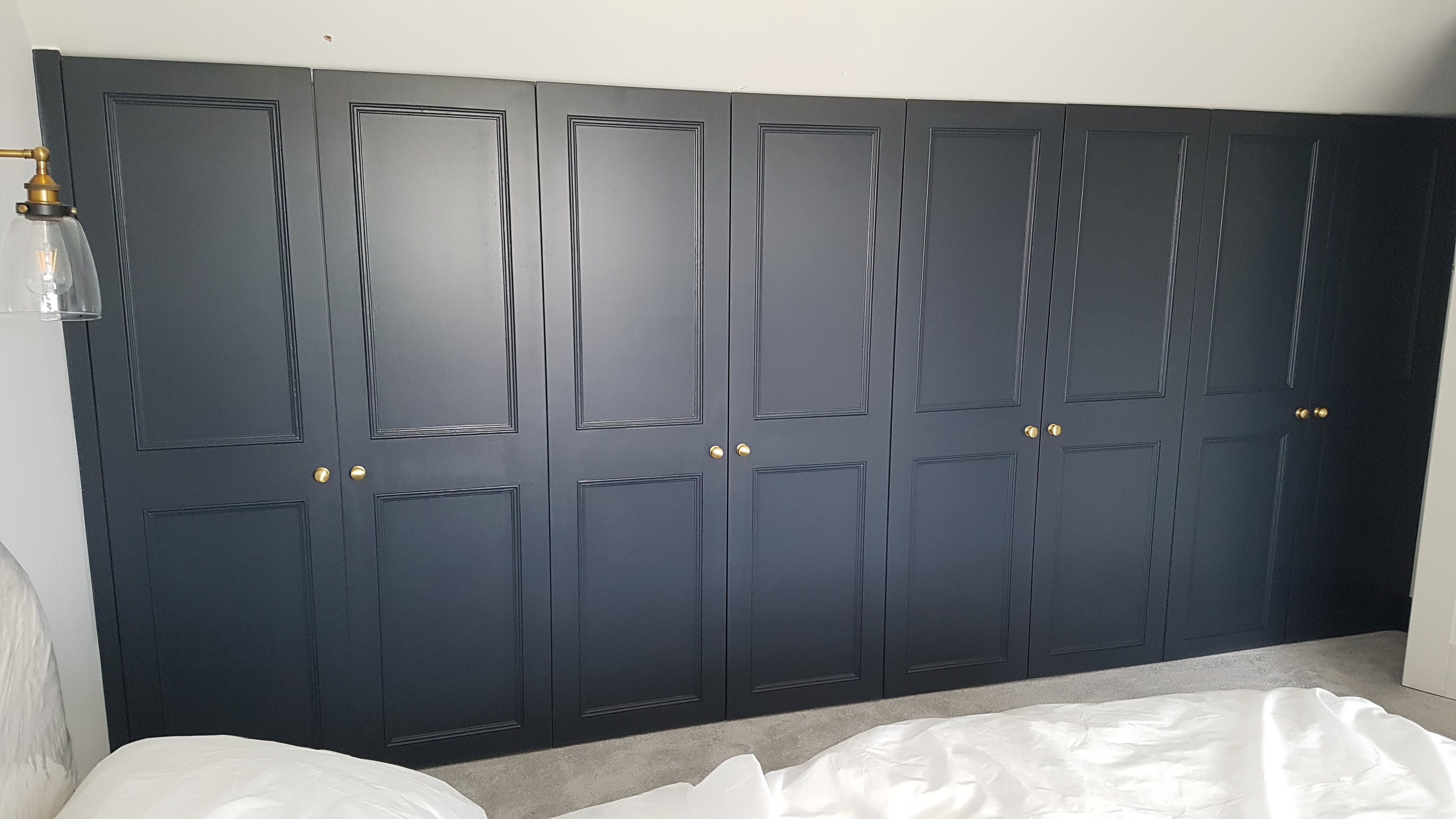 Traditional fitted wardrobe in Hague Blue with brass knobs in a bedroom