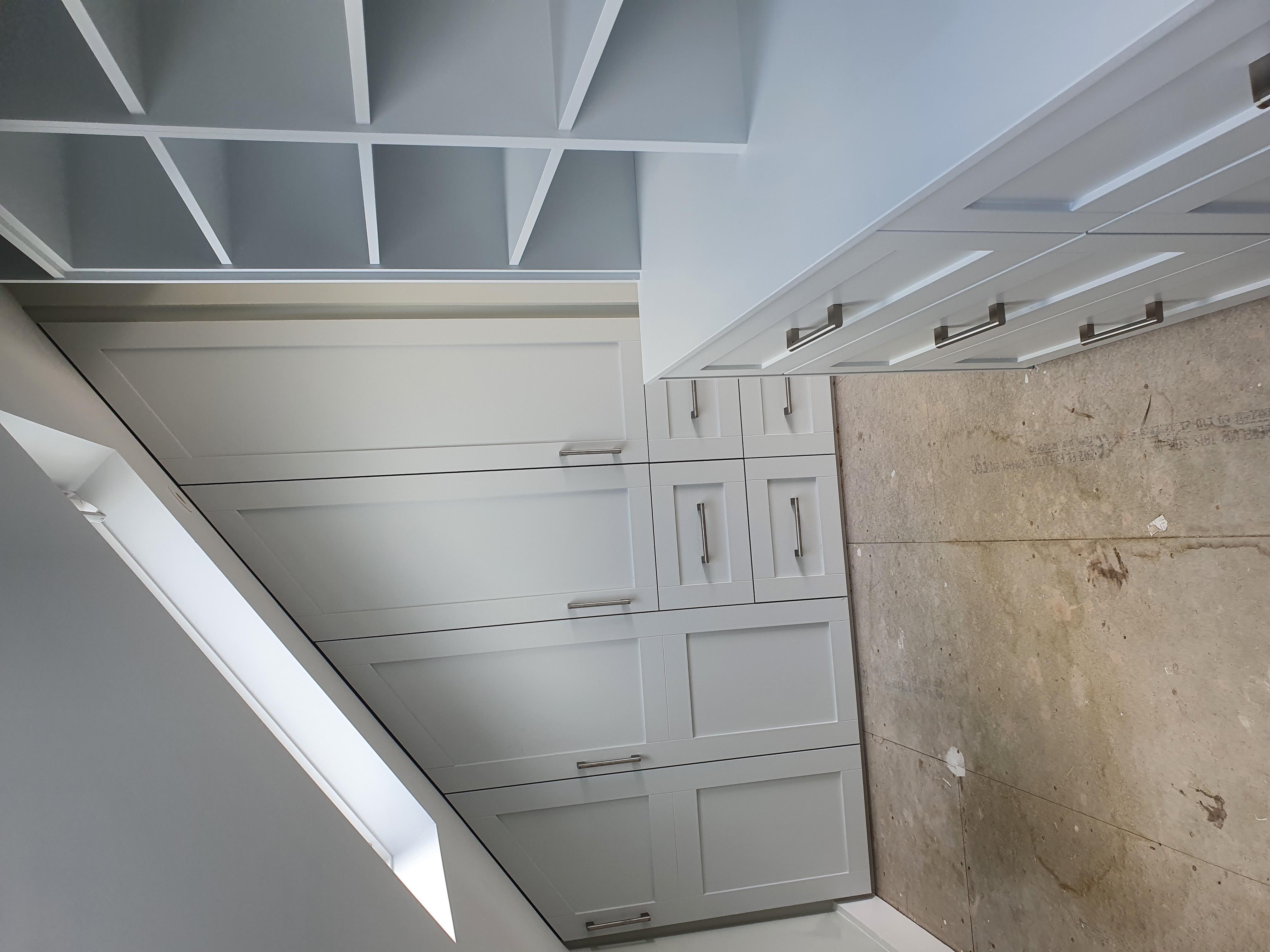Light grey shaker style fitted wardrobe with sloping ceiling adaptation for an attic bedroom, featuring brushed chrome bar handles.