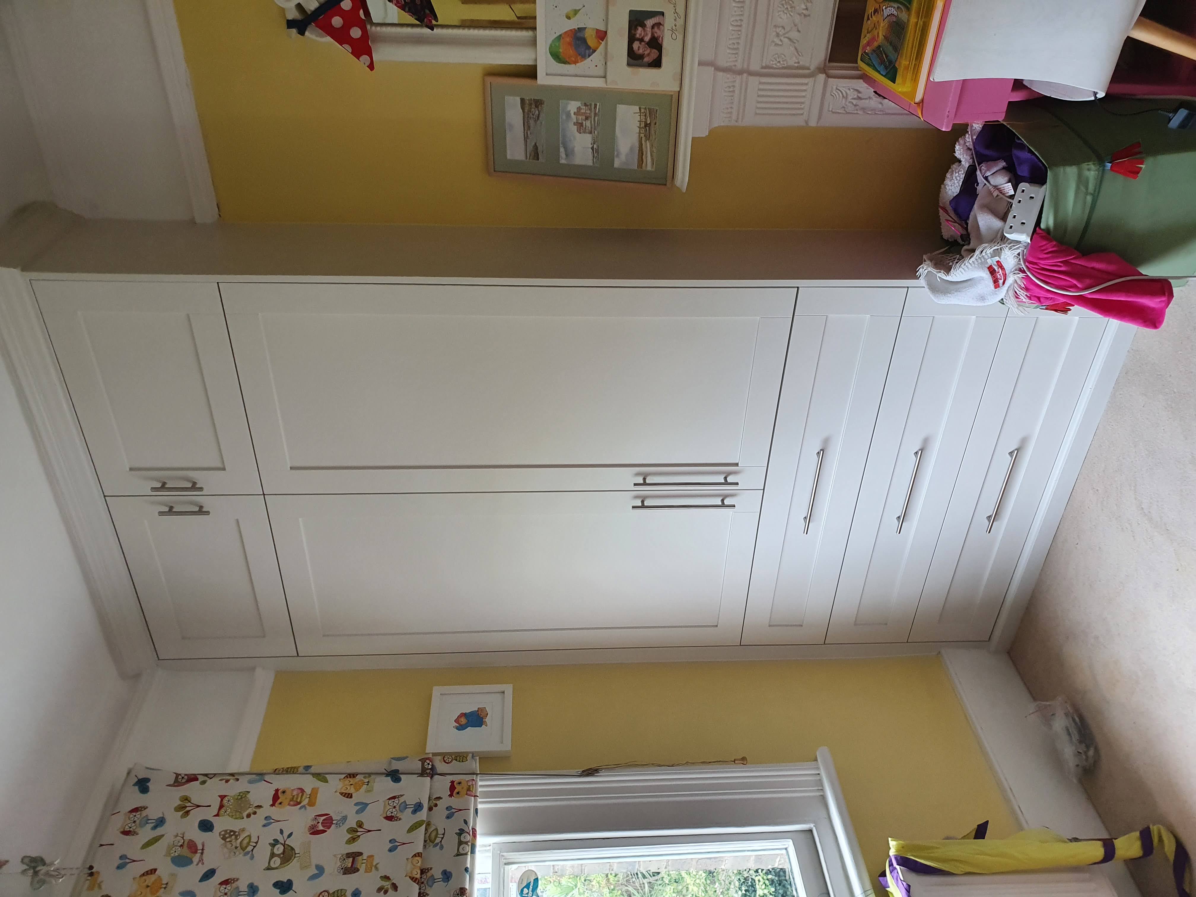 Fitted wardrobe in a timeless white Dulux paint, featuring shaker style doors and drawers with chrome bar handles, perfect for a modern bedroom.