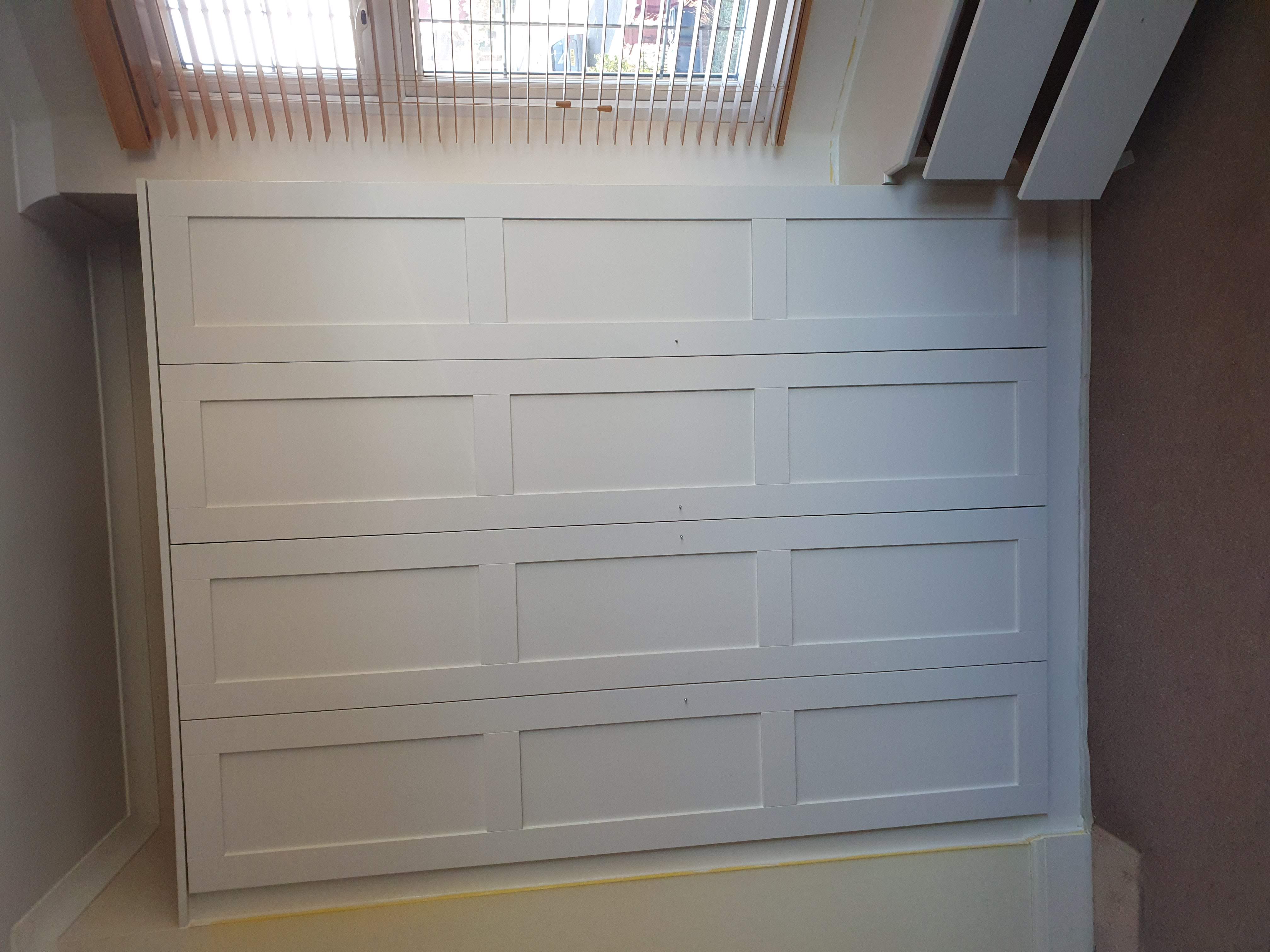 White Shaker style fitted wardrobe in a bedroom, offering seamless storage with push-to-open doors.