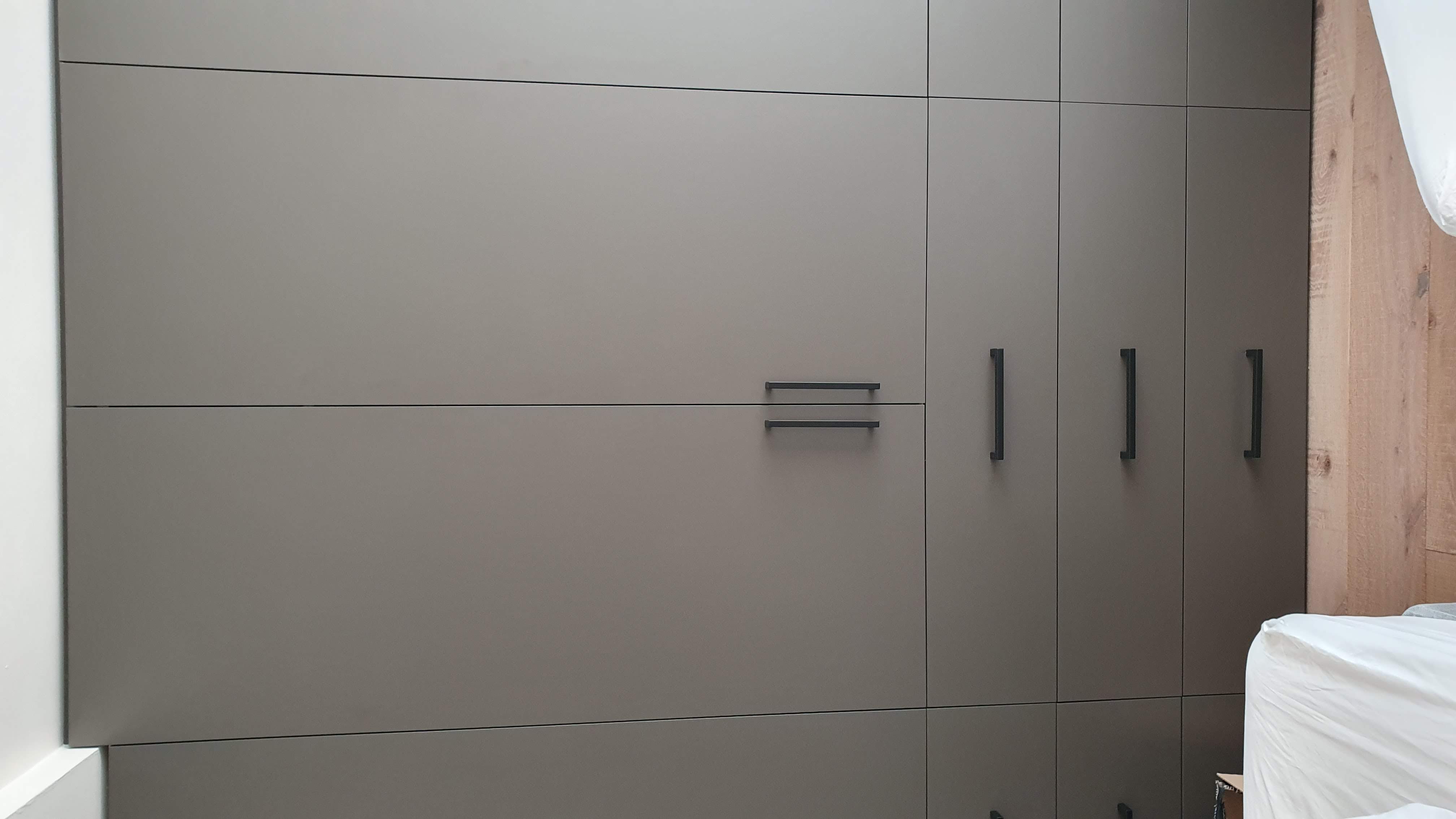 Modern fitted wardrobe in Elephant's Breath (greige) with matte black bar handles, perfect for a contemporary bedroom.
