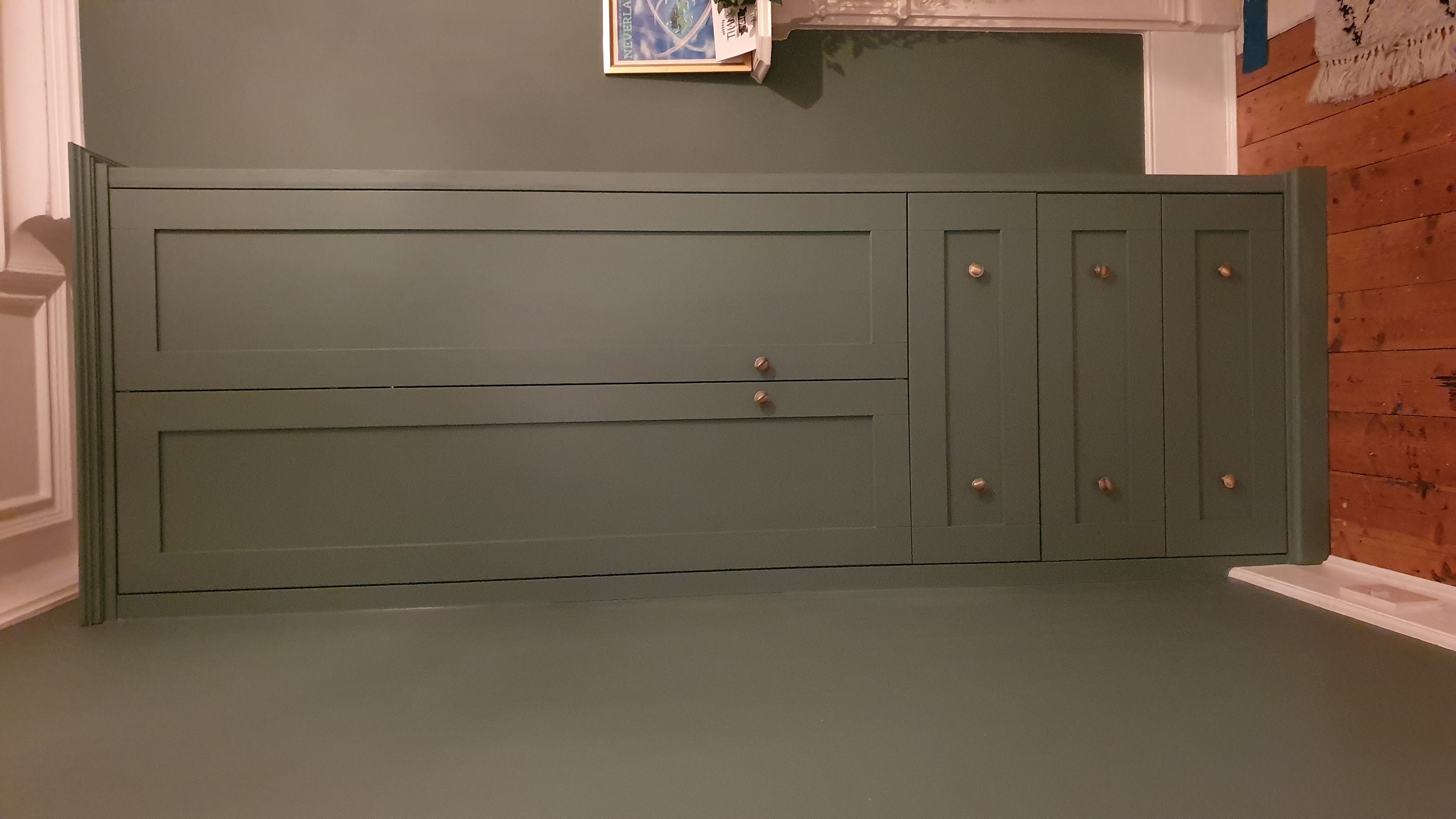 Shaker style fitted wardrobe in a deep Livid green with brass knobs, ideal for bedroom storage.