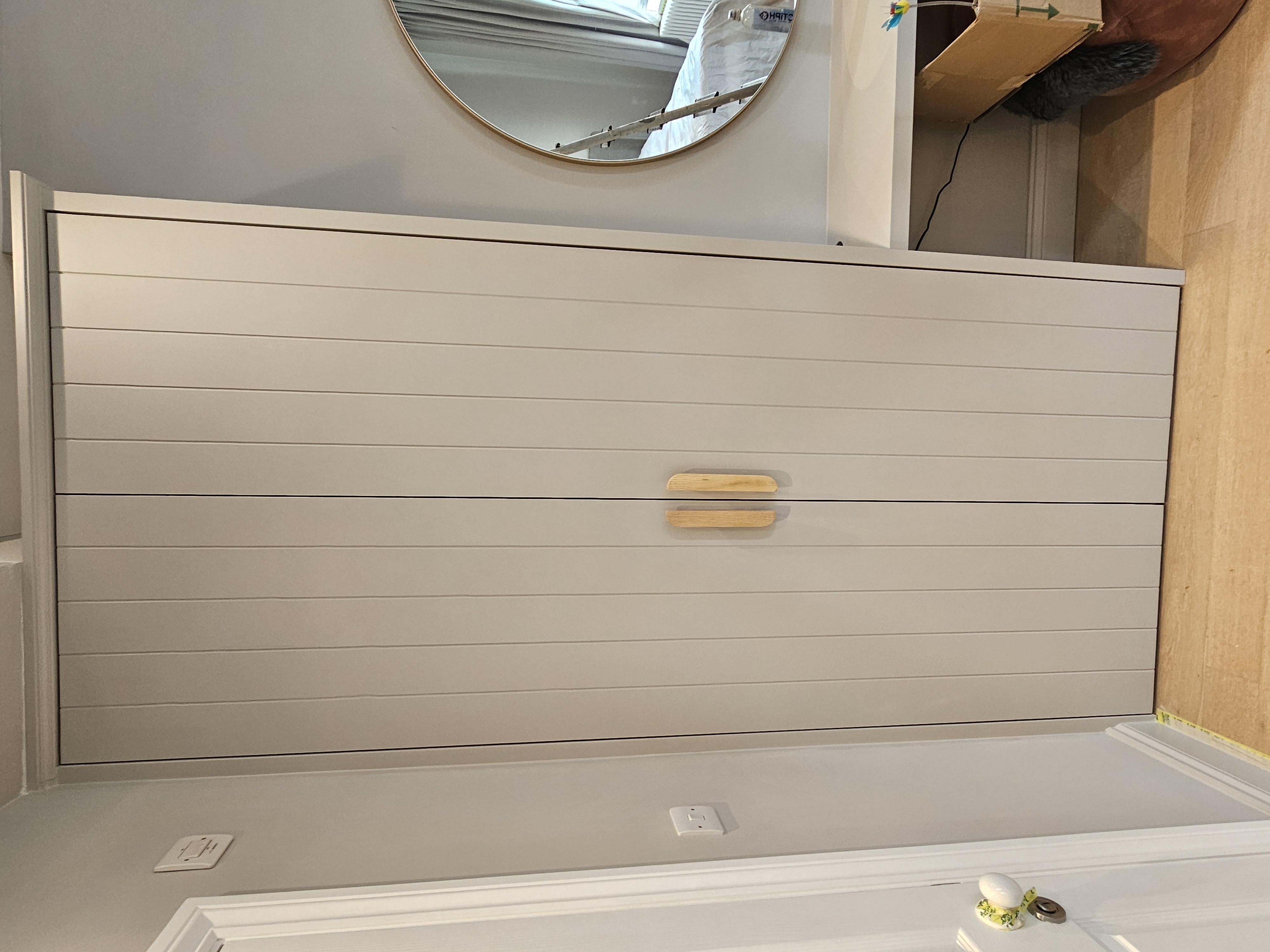 Fitted wardrobe in Dulux Goose Down grey paint with shaker style doors and wooden bar handles, located in a bedroom.