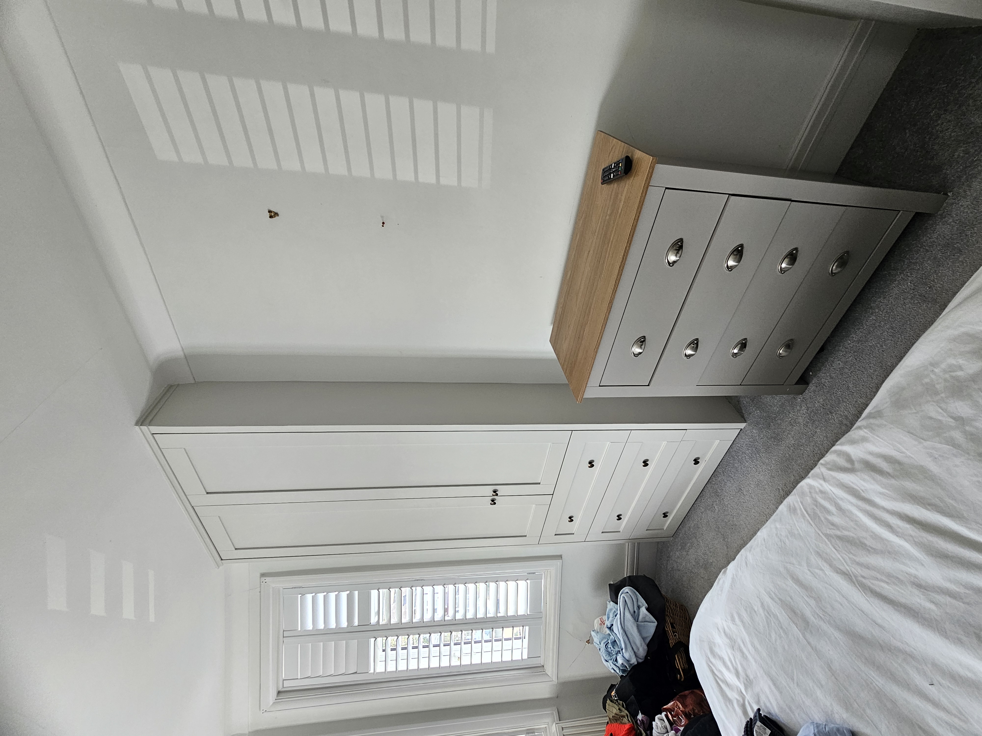 Shaker style fitted wardrobe in a soft cream color with black knobs, offering ample storage for a modern bedroom.