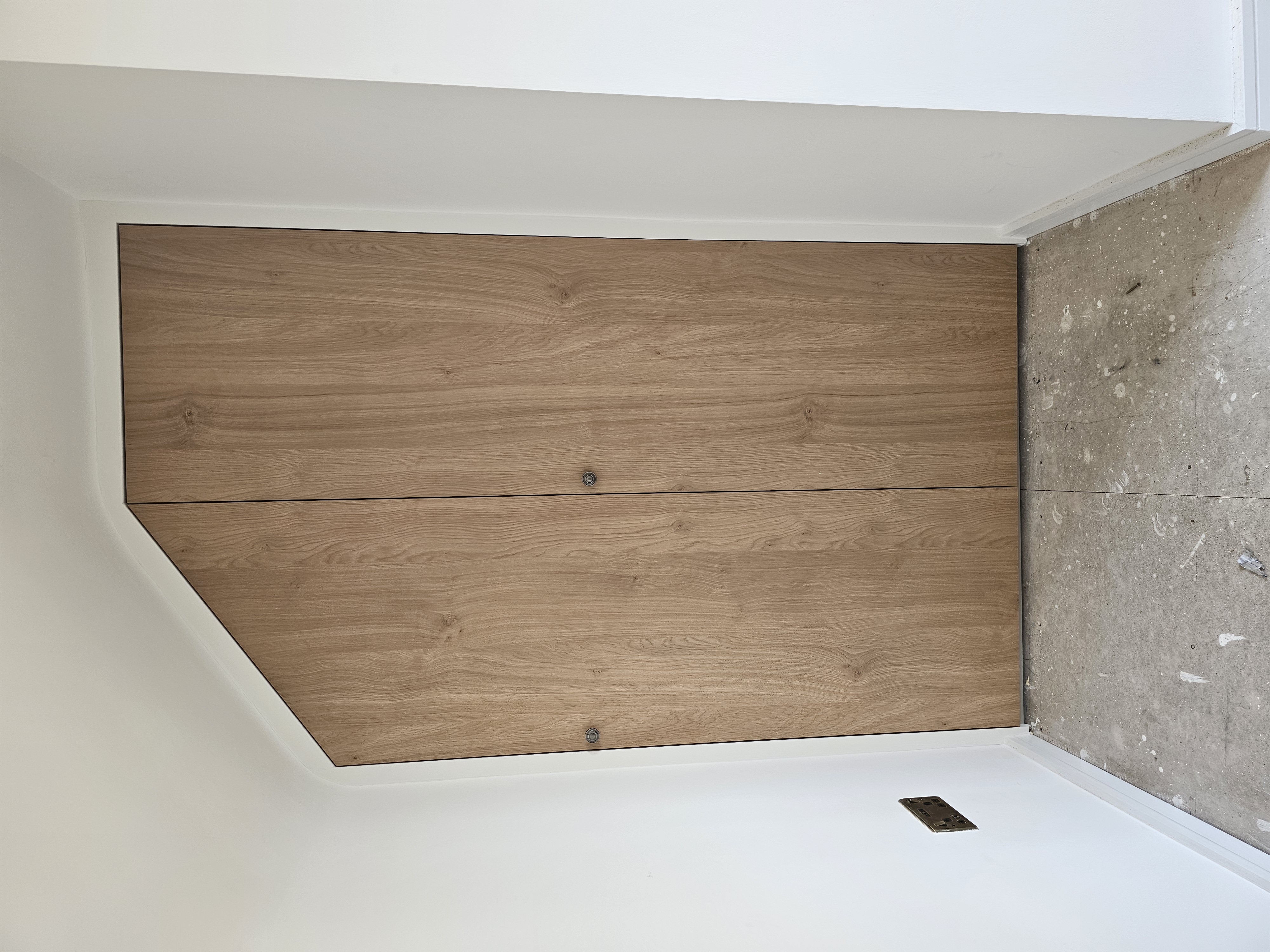 Modern natural oak fitted wardrobe with sloped top for attic storage in a bedroom.