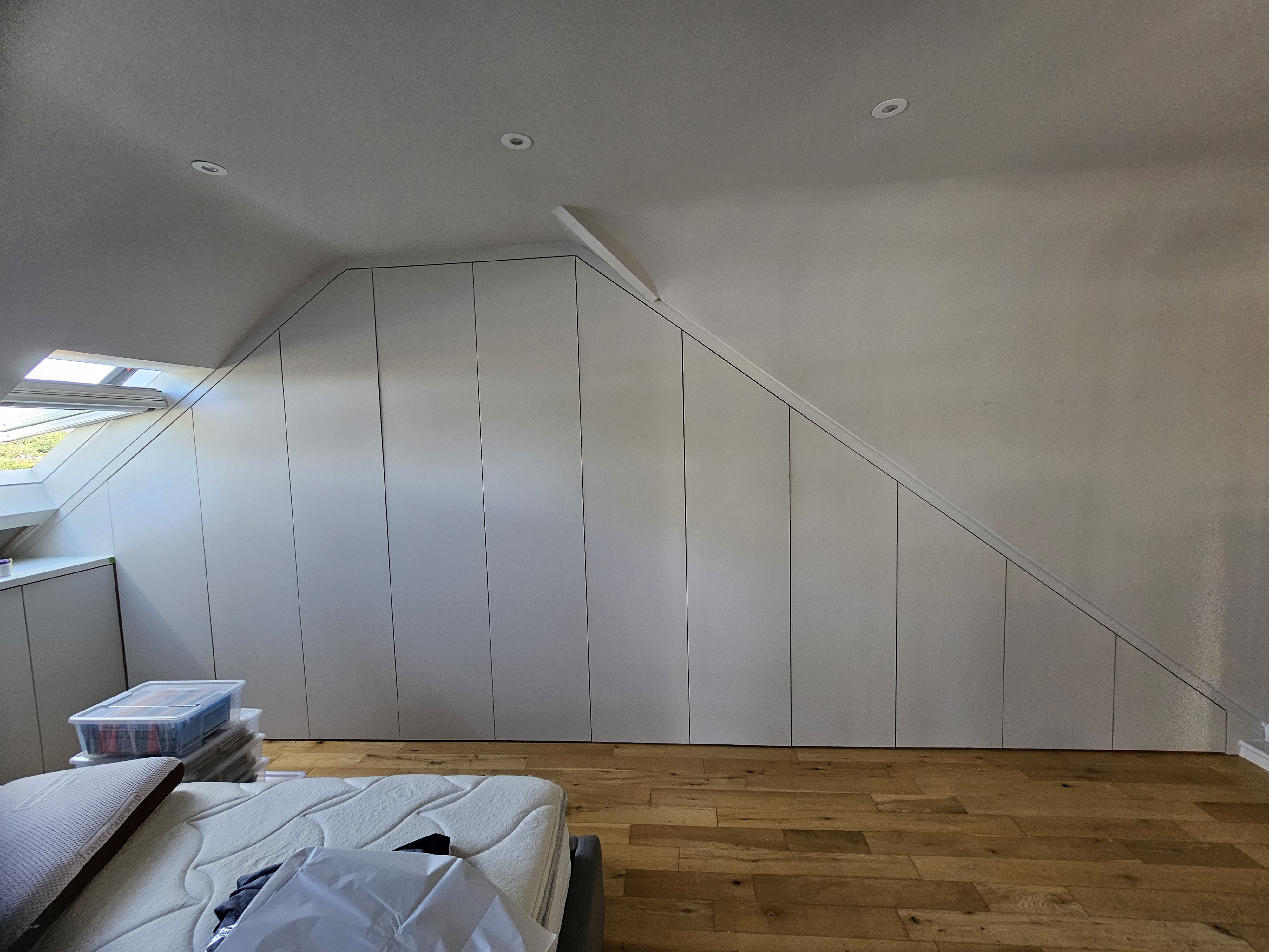 Minimalist Soft White fitted wardrobe in a bedroom with a sloping ceiling.