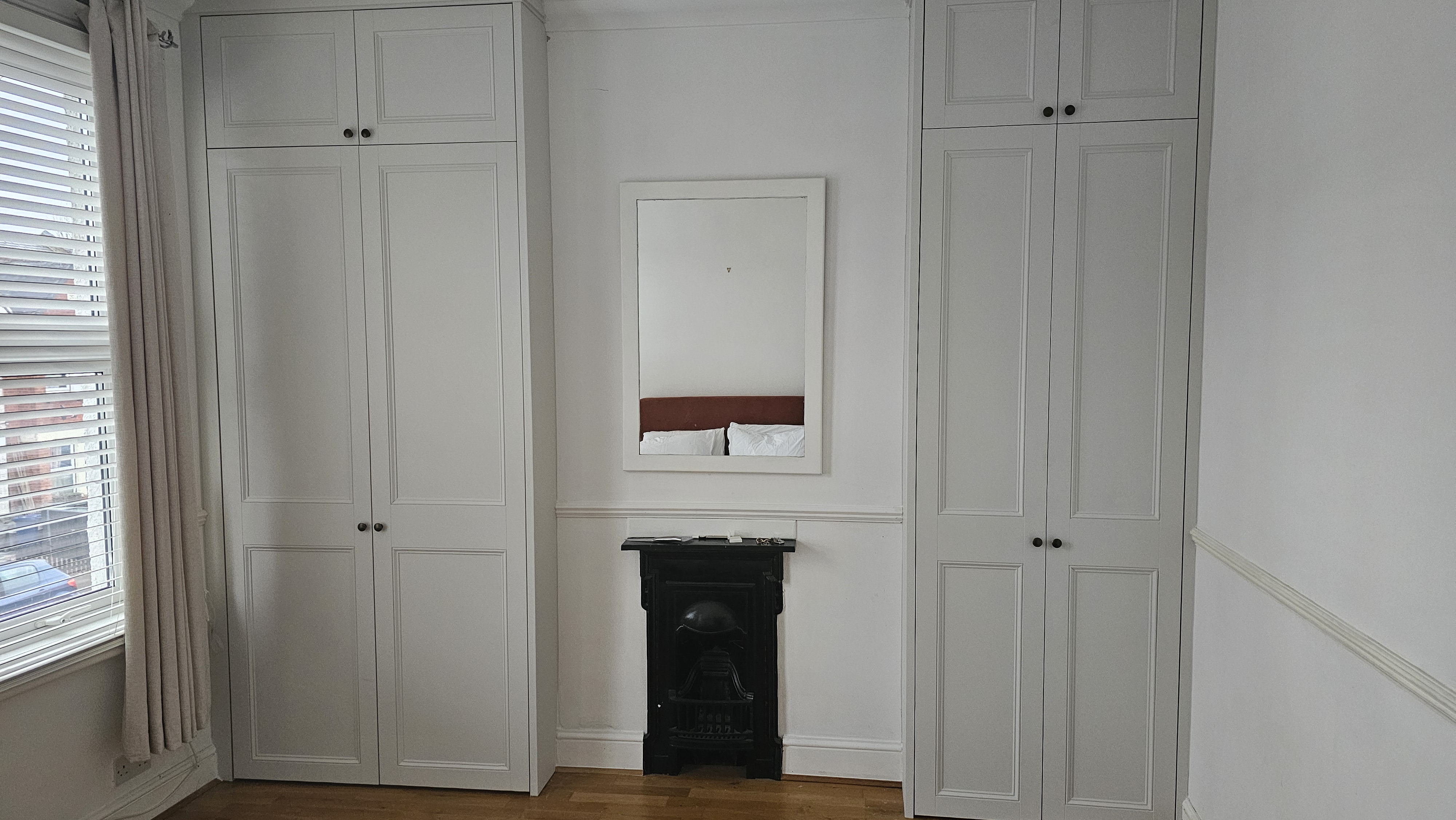Two traditional fitted alcove wardrobes in Slaked Lime white, perfect for a period style bedroom, with black knob hardware.