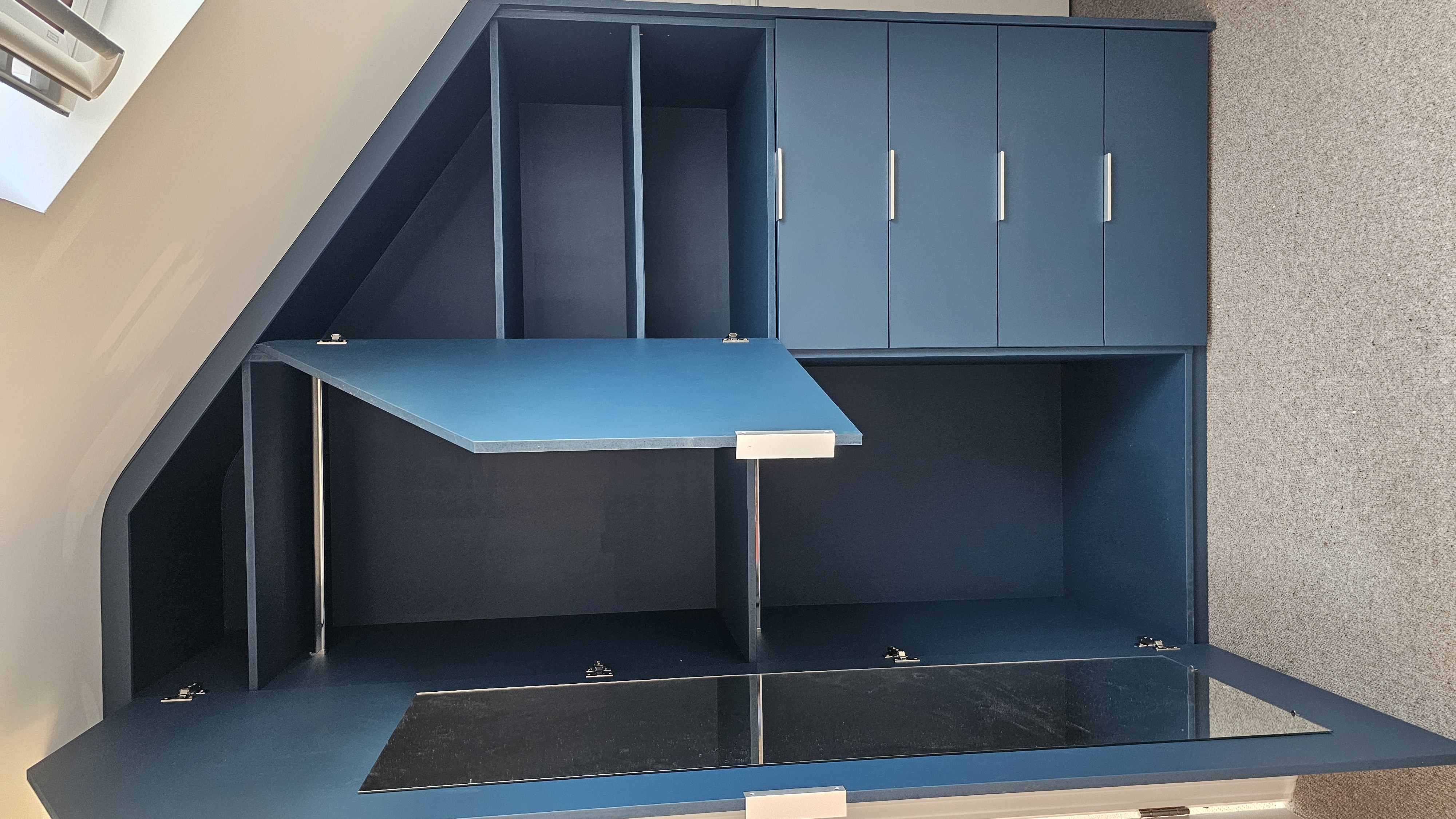 Contemporary fitted wardrobe in Hague Blue for sloped bedroom ceilings, featuring integrated drawers, hanging space, and a mirrored door.