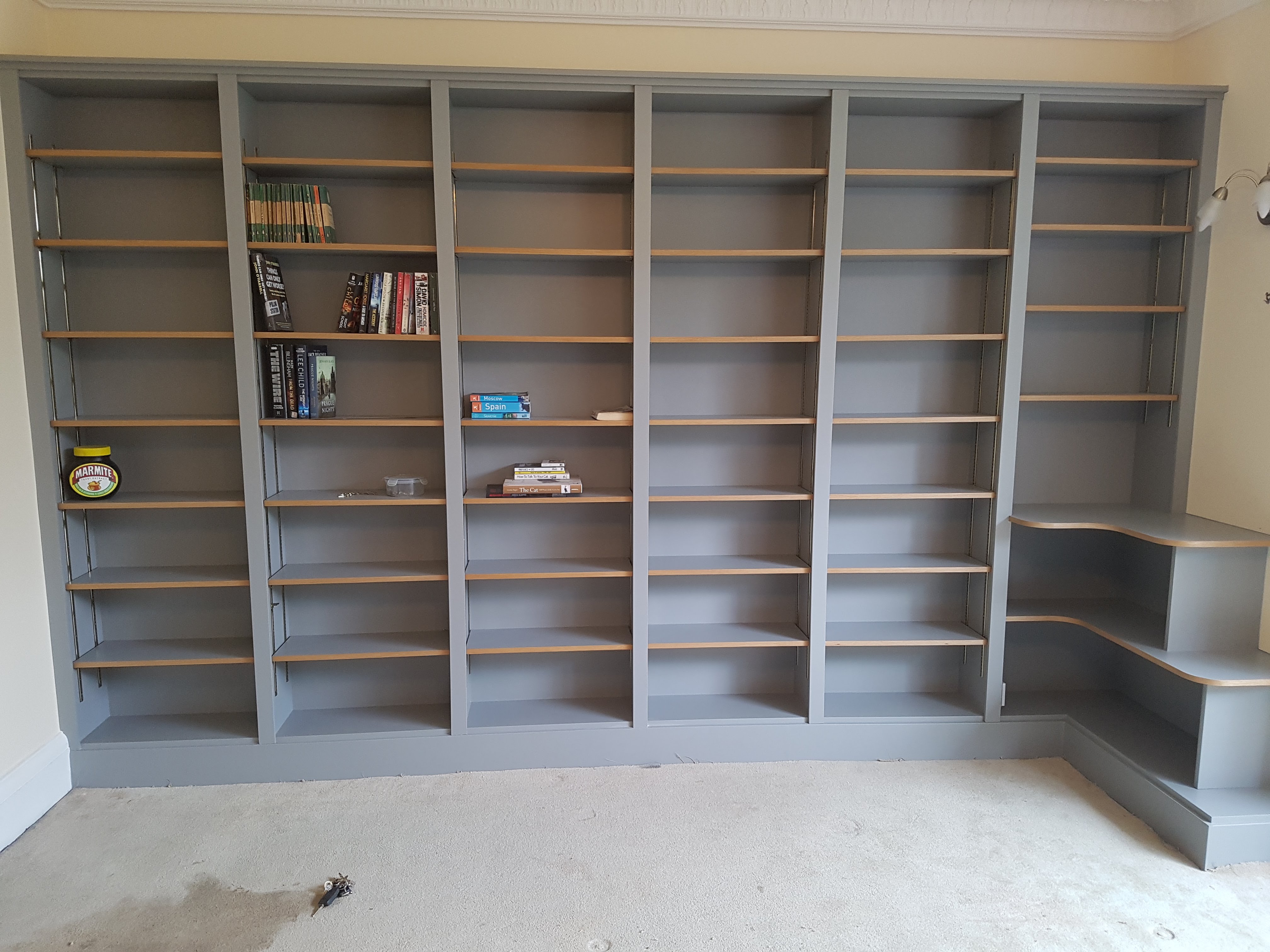 Modern fitted bookcase in Farrow and Ball Railings grey with adjustable wood shelves, perfect for a living room.
