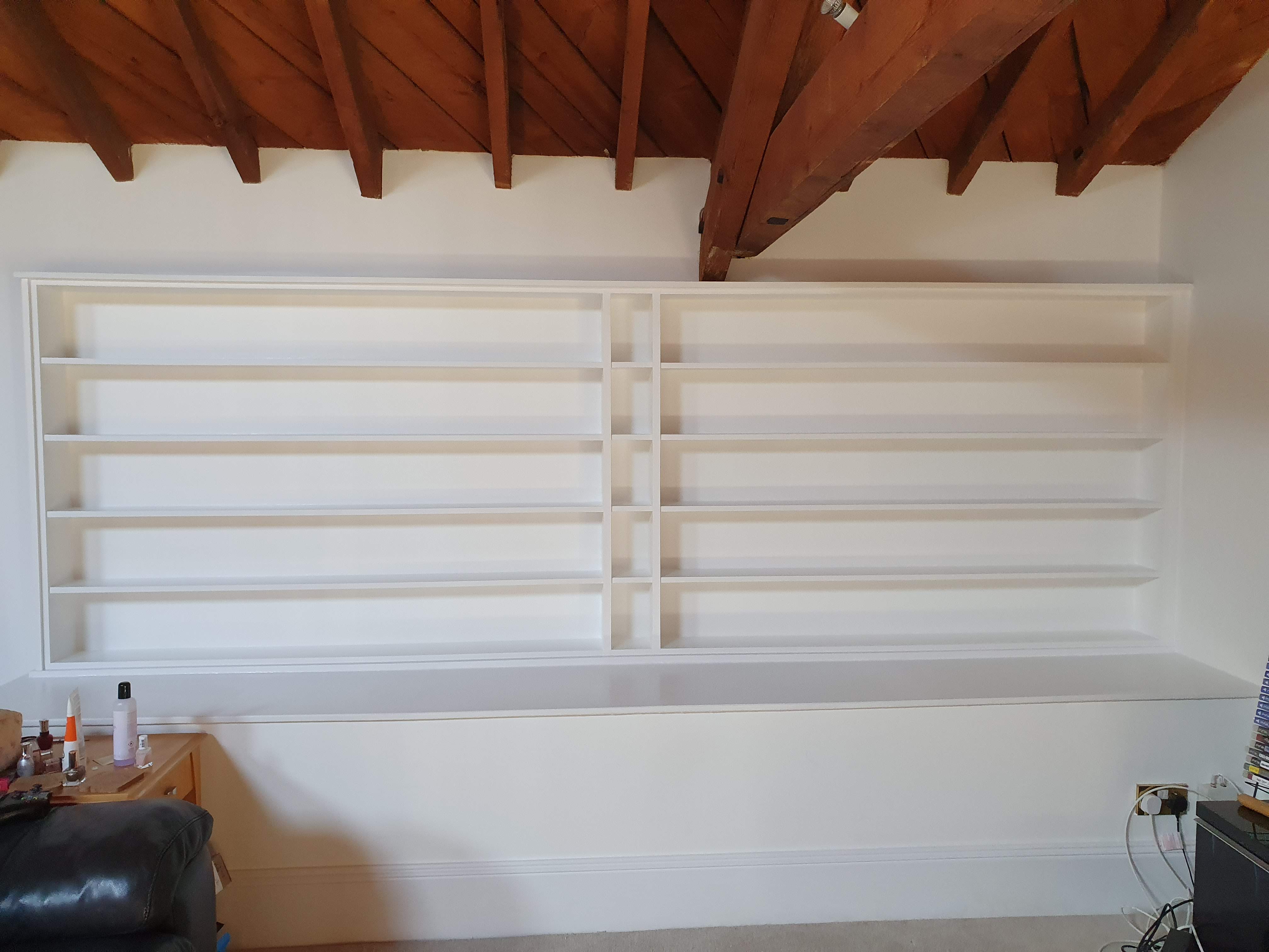 Contemporary white fitted bookcase in a living room, featuring open shelving and a minimalist design.