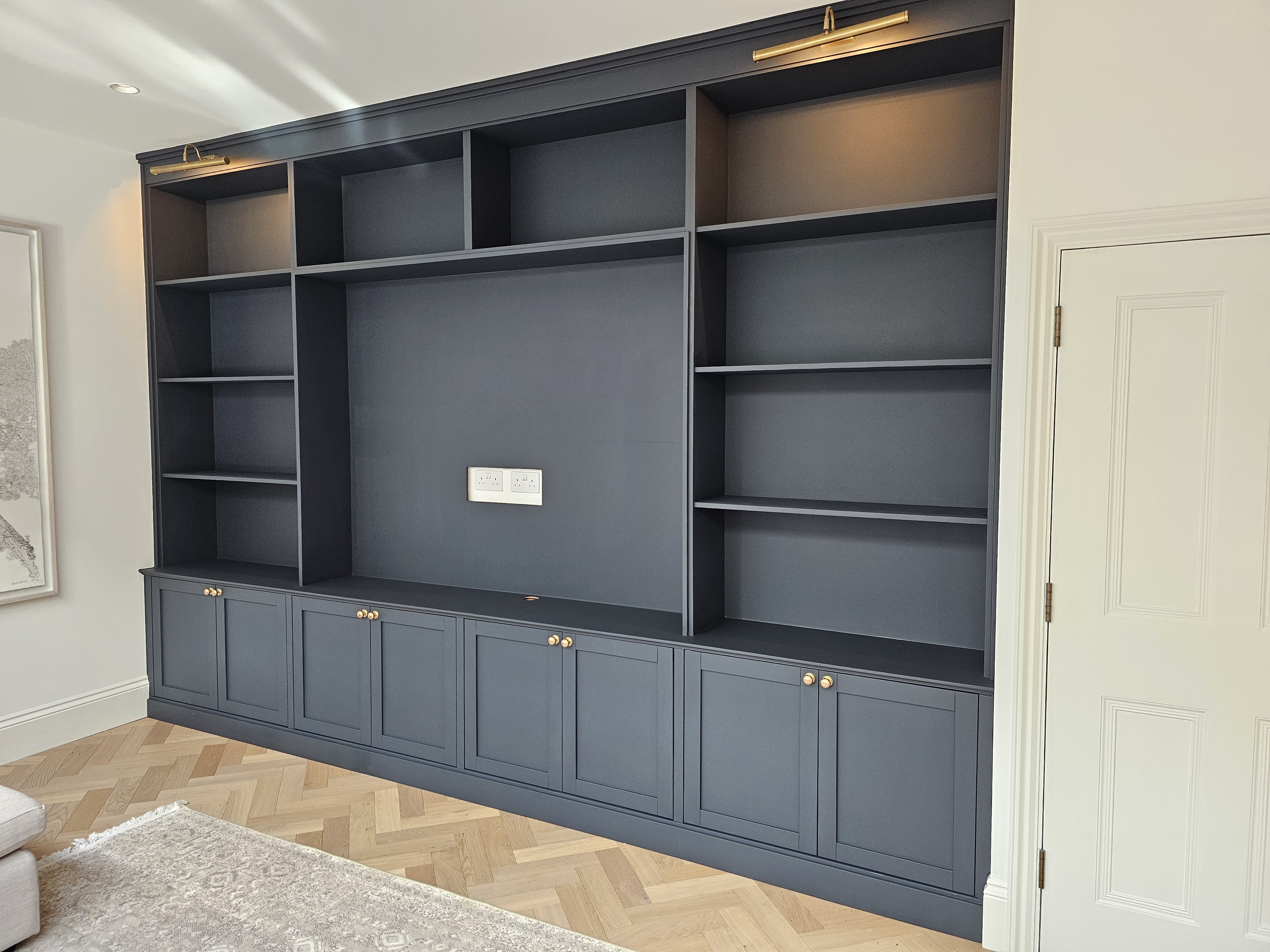 Traditional Hague Blue built-in media unit and bookcase with brass knobs in a living room.