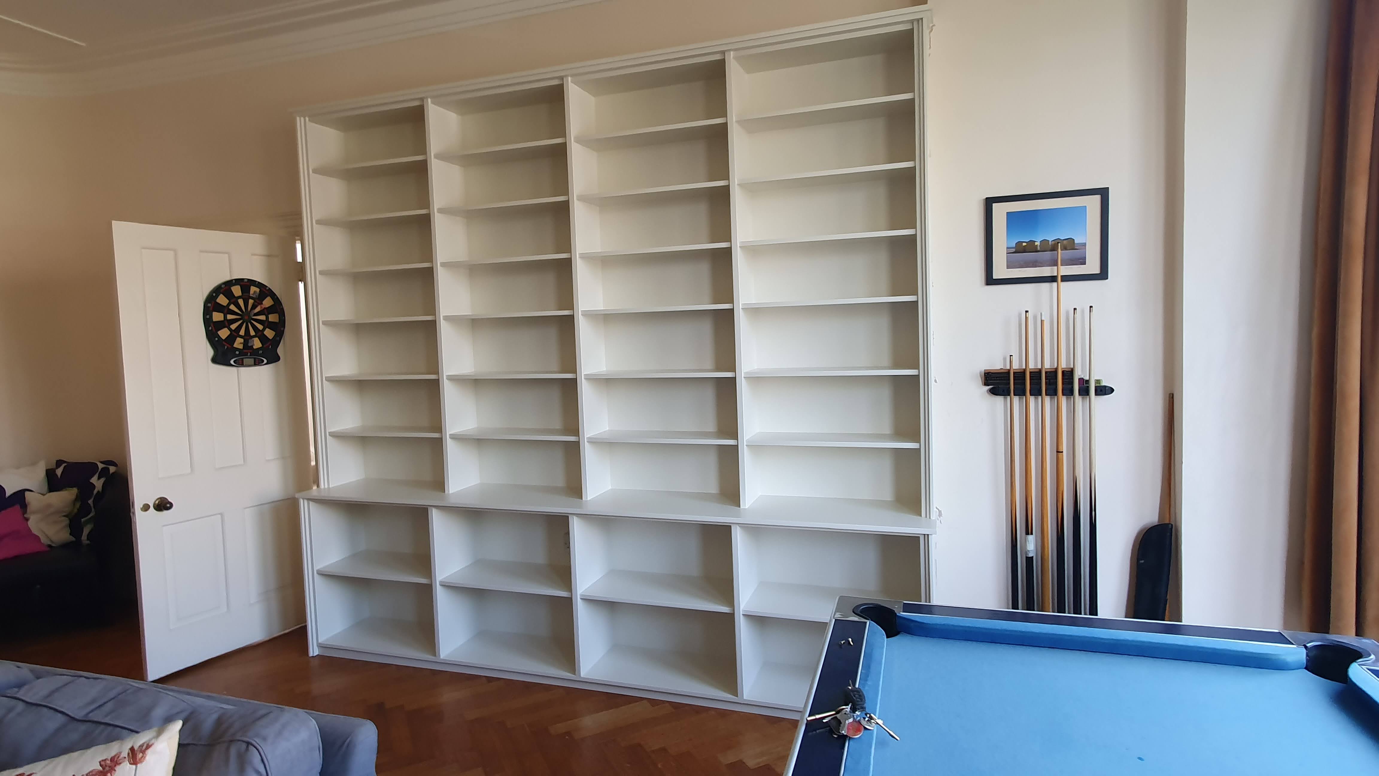 Large traditional fitted bookcase in Timeless white, spanning a living room wall with multiple shelves.