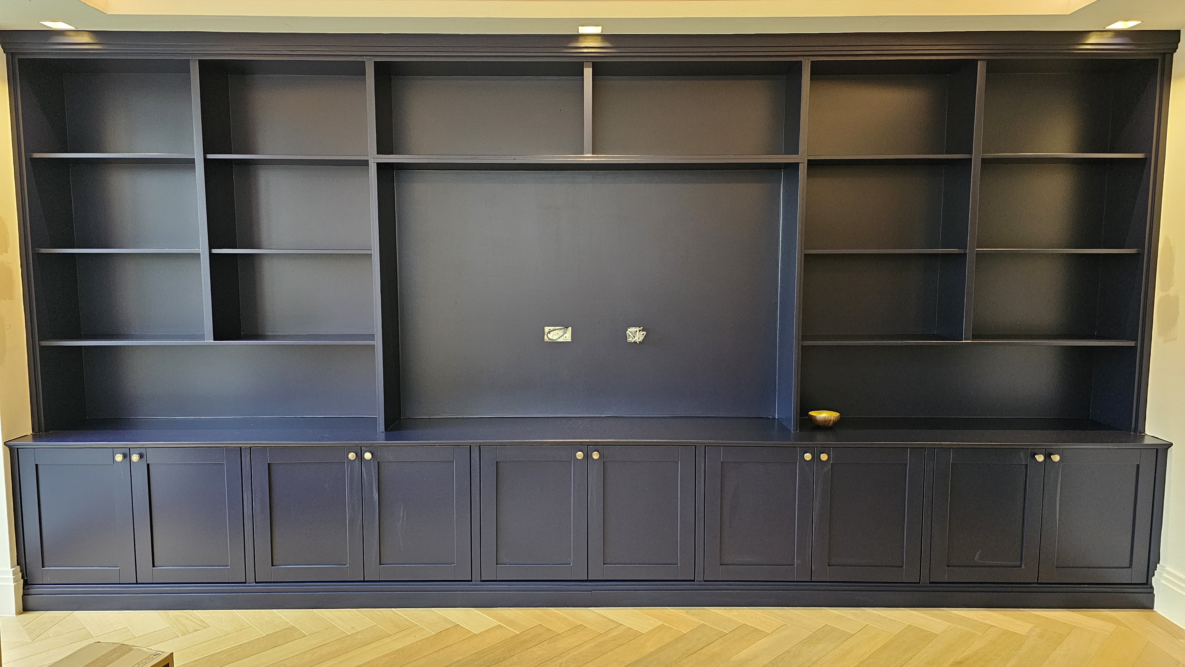 Traditional built-in storage and media unit painted in Farrow and Ball Hague Blue, featuring shaker style doors and brass knobs.